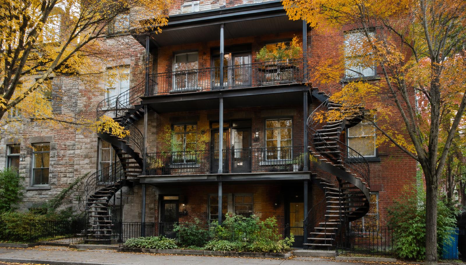 Triplex montréalais en brique avec escaliers extérieurs en colimaçon, en automne